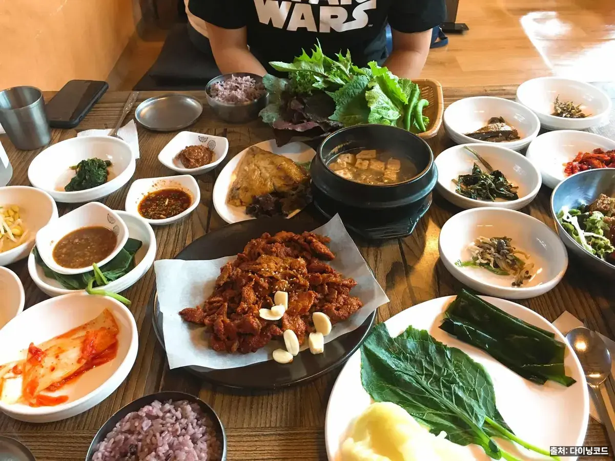 유수정 석쇠불고기 쌈밥 한상, 쌈채소와 된장찌개·나물 반찬이 나무 상 위에 깔린 모습